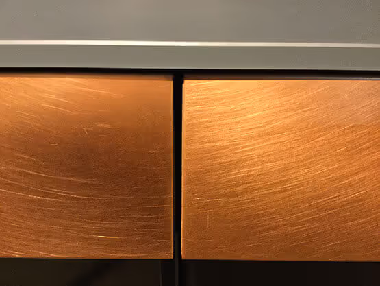 Acabados metálicos MOLTENI-VERNICI en superficie de madera dorada con textura