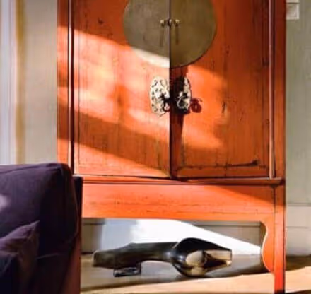 MOLTENI-VERNICI Speziallacke: Orangefarbener Schrank mit Sonnenlicht und dunkler Dekoration