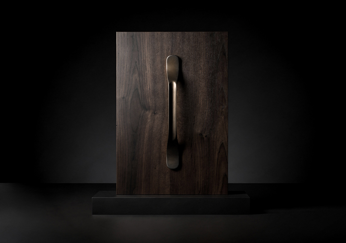 Maniglia metallica con Finitura Molteni Vernici su tavola di legno con illuminazione drammatica