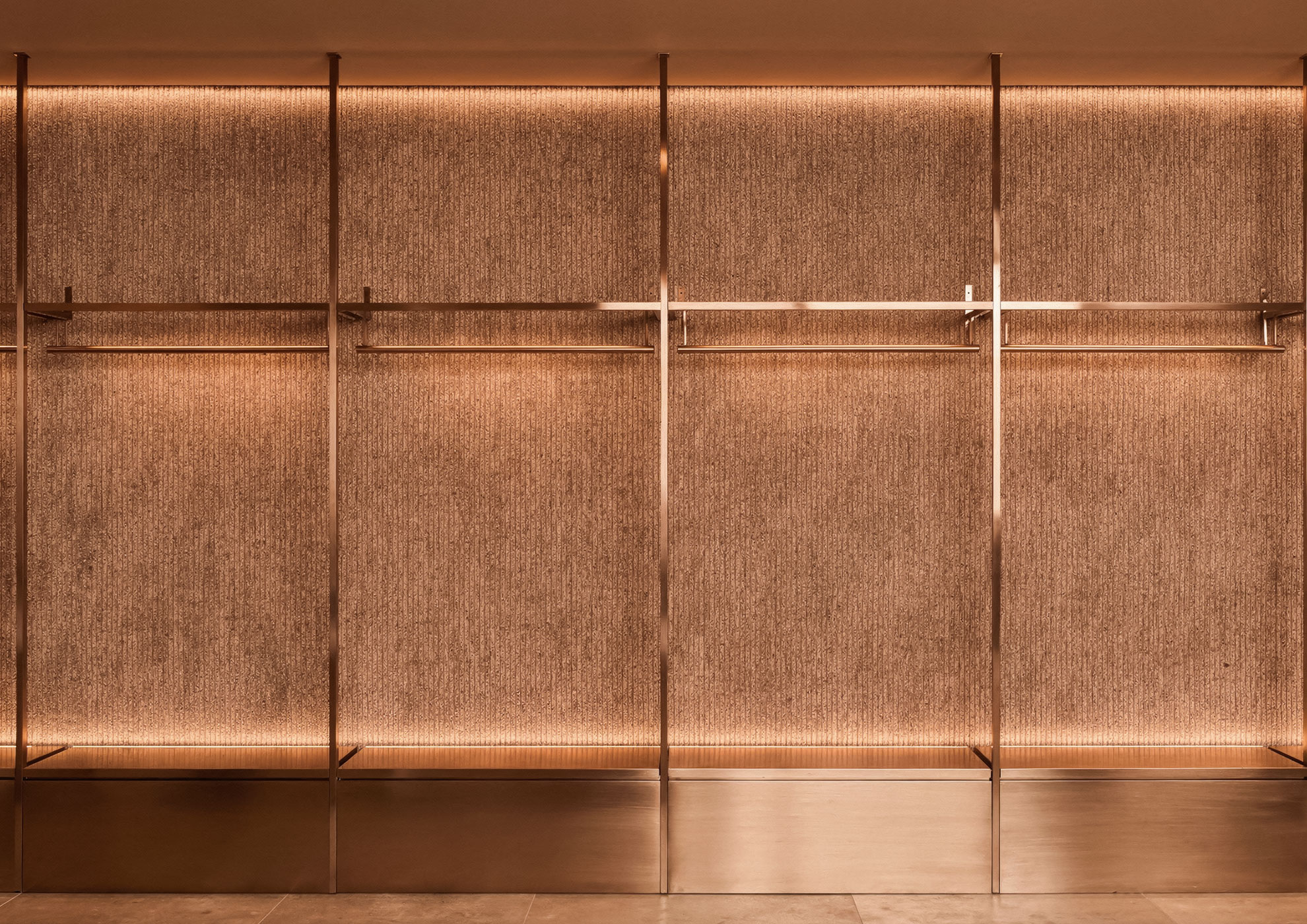 Modular wall in brushed copper with Never Brushed finish Molteni Vernici, luxury decorative system for contemporary retail design that enhances the materiality and chromatic depth of the metallic surface.