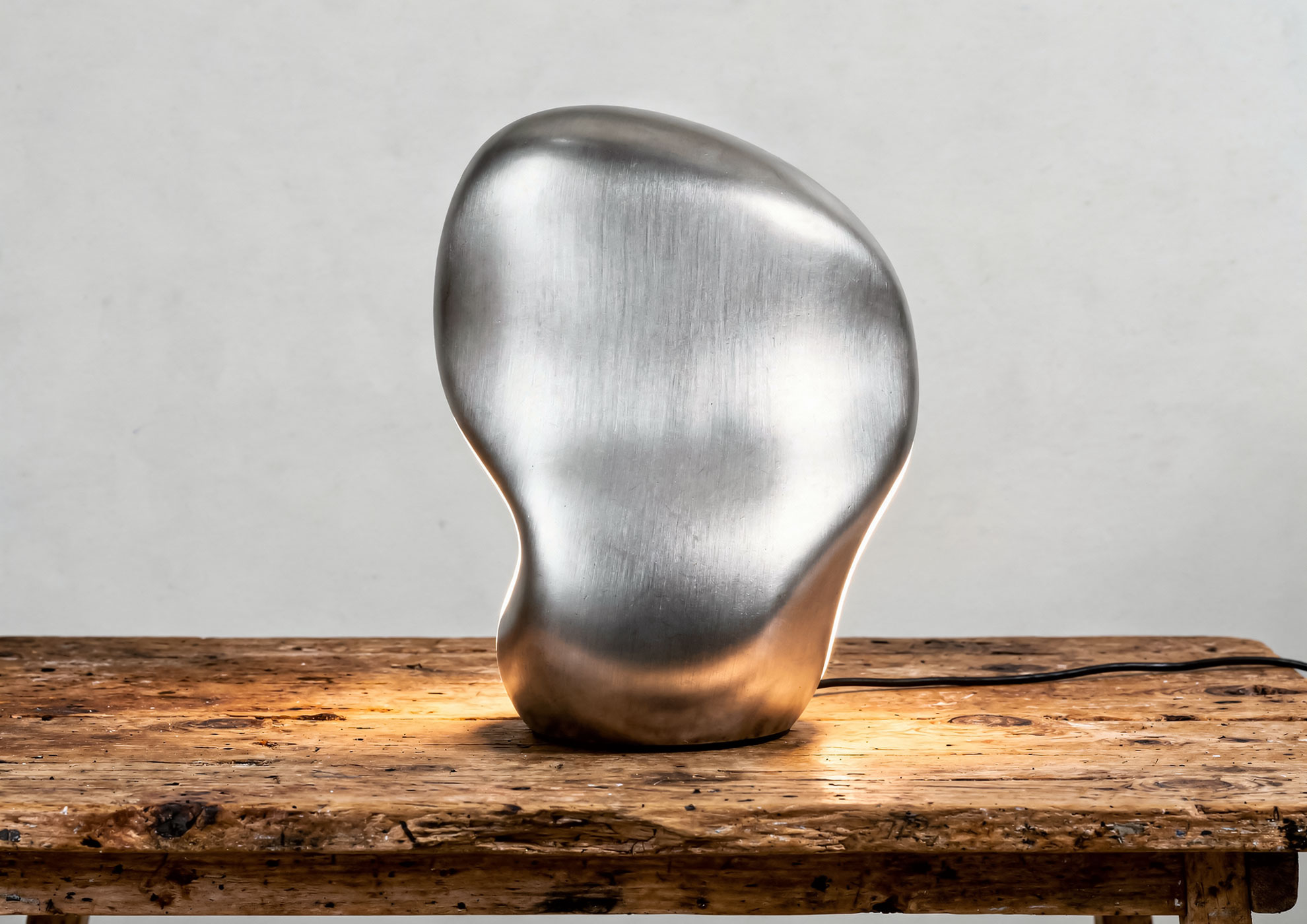 Sculptural decorative lamp with Never Brushed brushed metal effect finish in silver by Molteni Vernici, premium surface that enhances contemporary design on natural wood base.