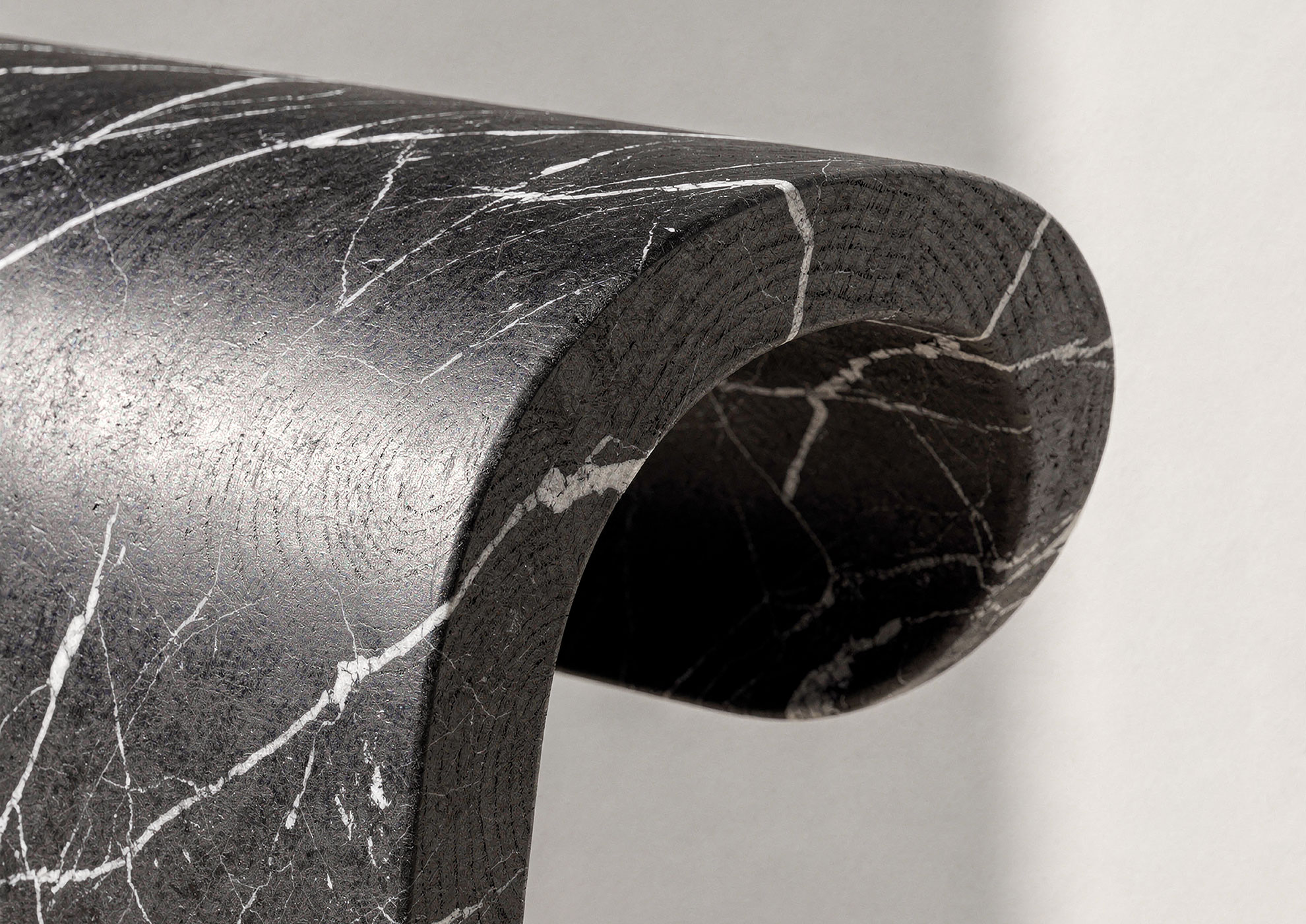 Close-up of STONAIR curved black marble surface with white veining.