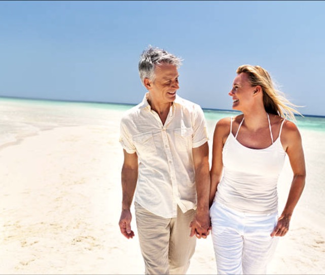 Image of two people holding hands on the beach
