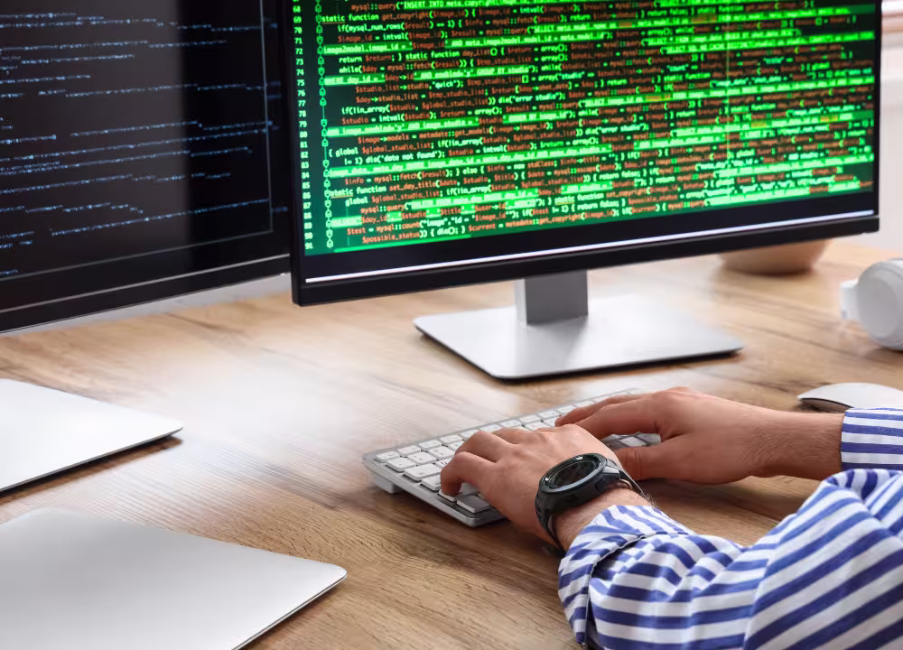 Person coding at a dual-monitor workstation, illustrating Snyk's customer story with Tropic