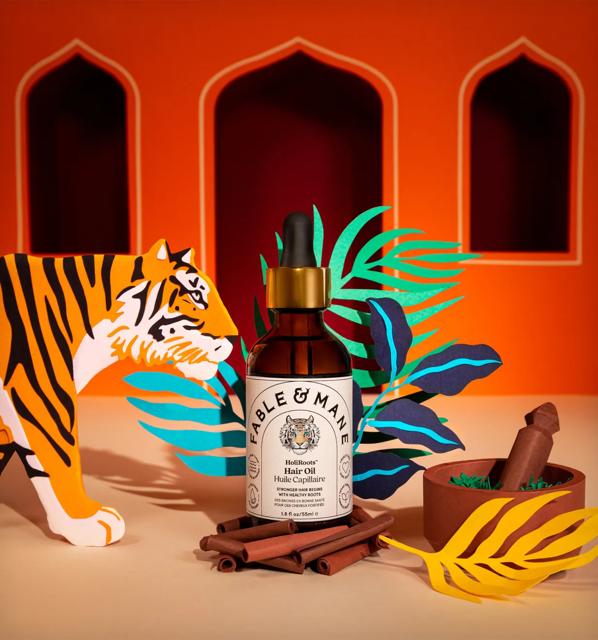 Bottle of Fable & Mane HoliRoots Hair Oil staged with paper tiger and jungle leaf props.