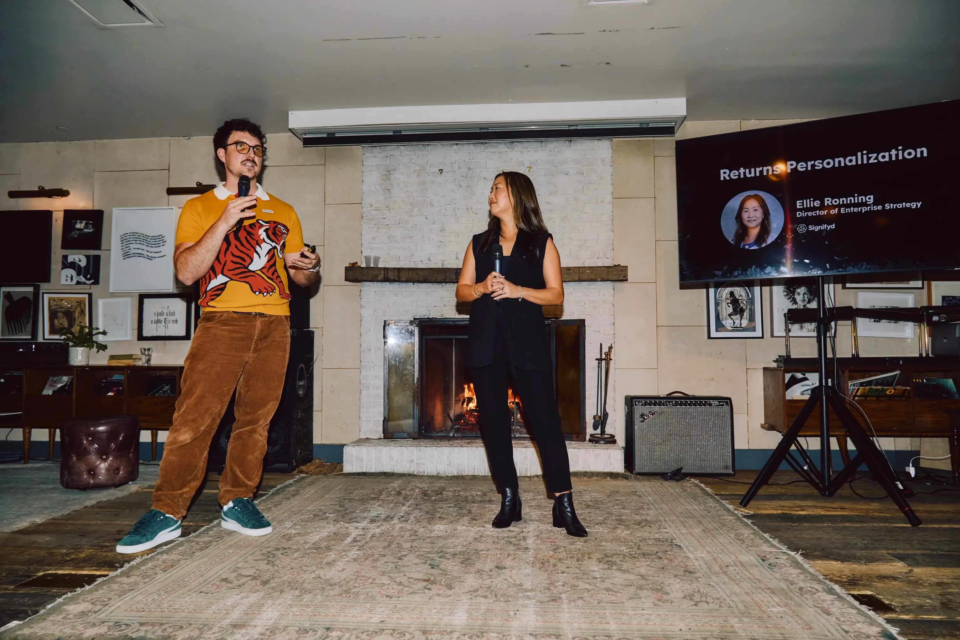 Two speakers presenting on returns and personalization in front of a fireplace at an ehouse event.