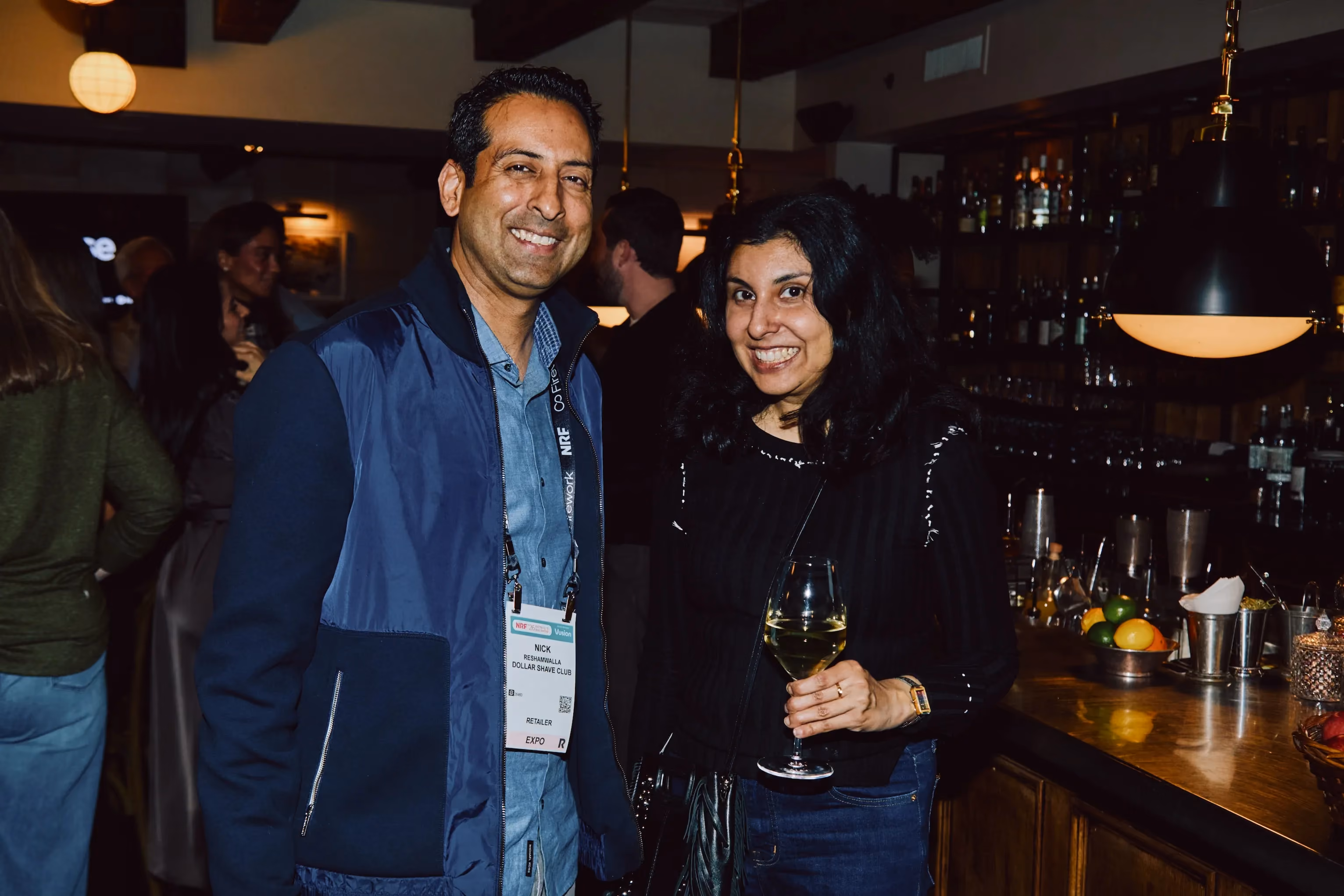 Two attendees smiling together at the bar during an ehouse networking event.