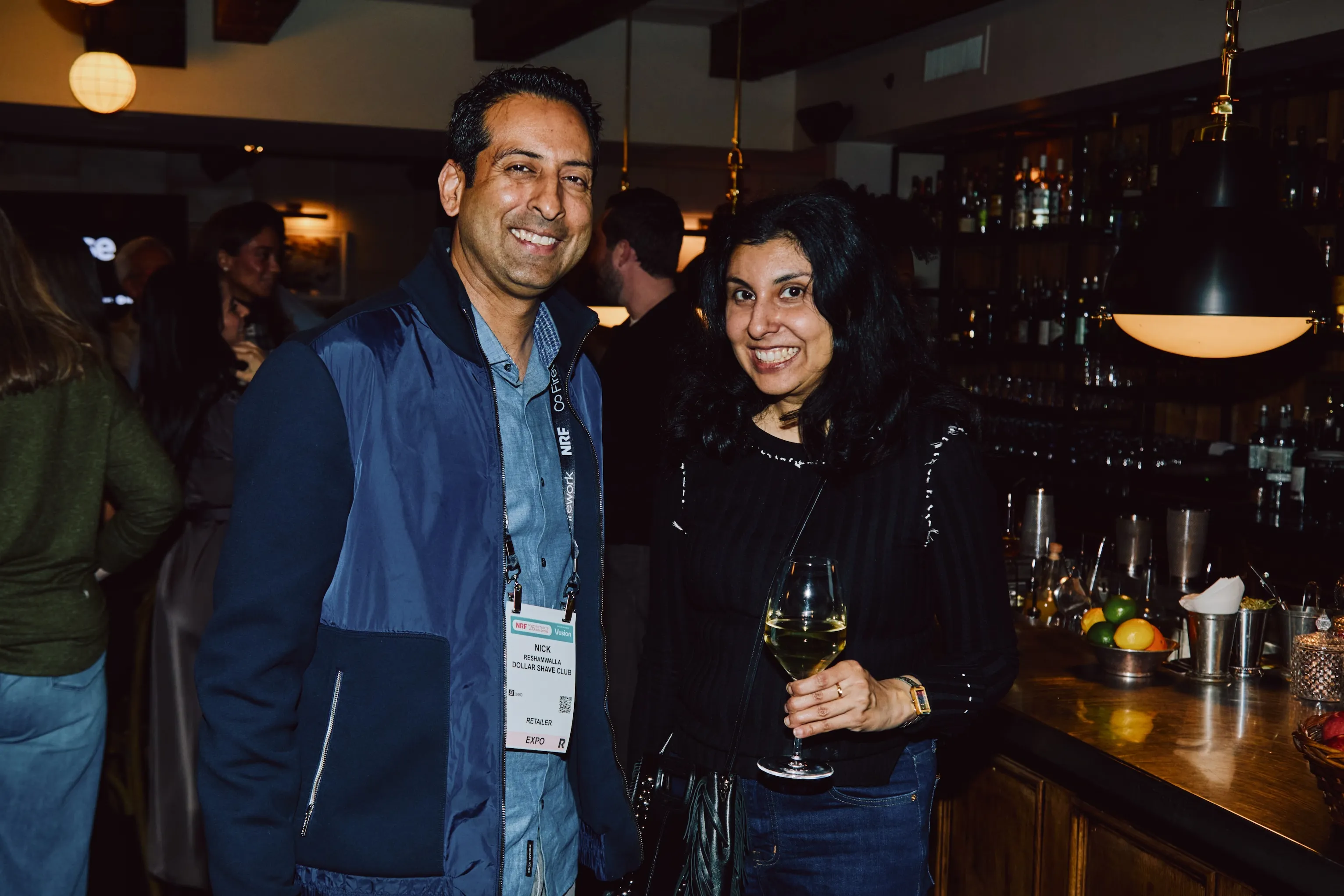 Two attendees smiling together at the bar during an ehouse networking event.