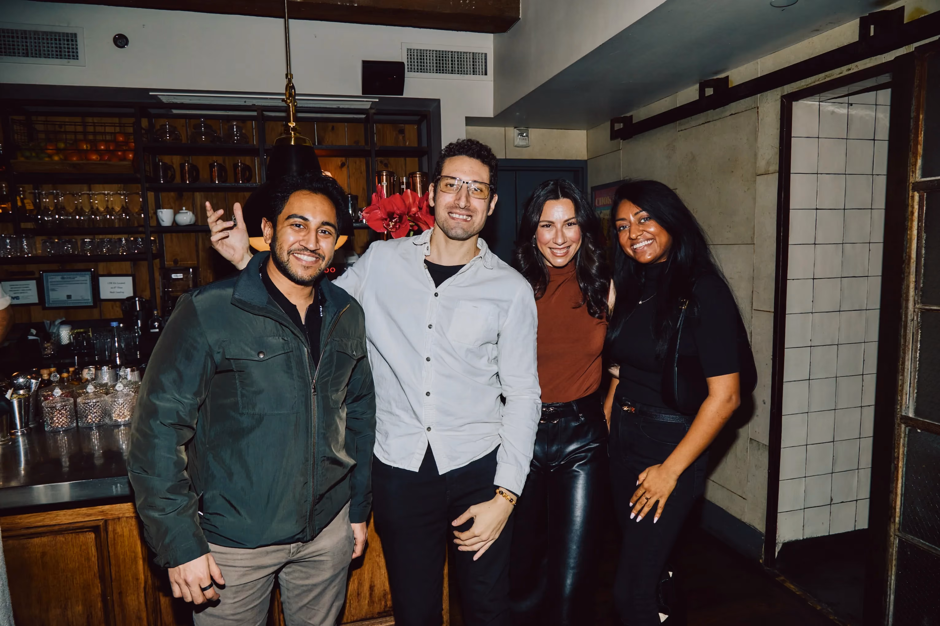 Four colleagues posing together at a bar during an ehouse team party.
