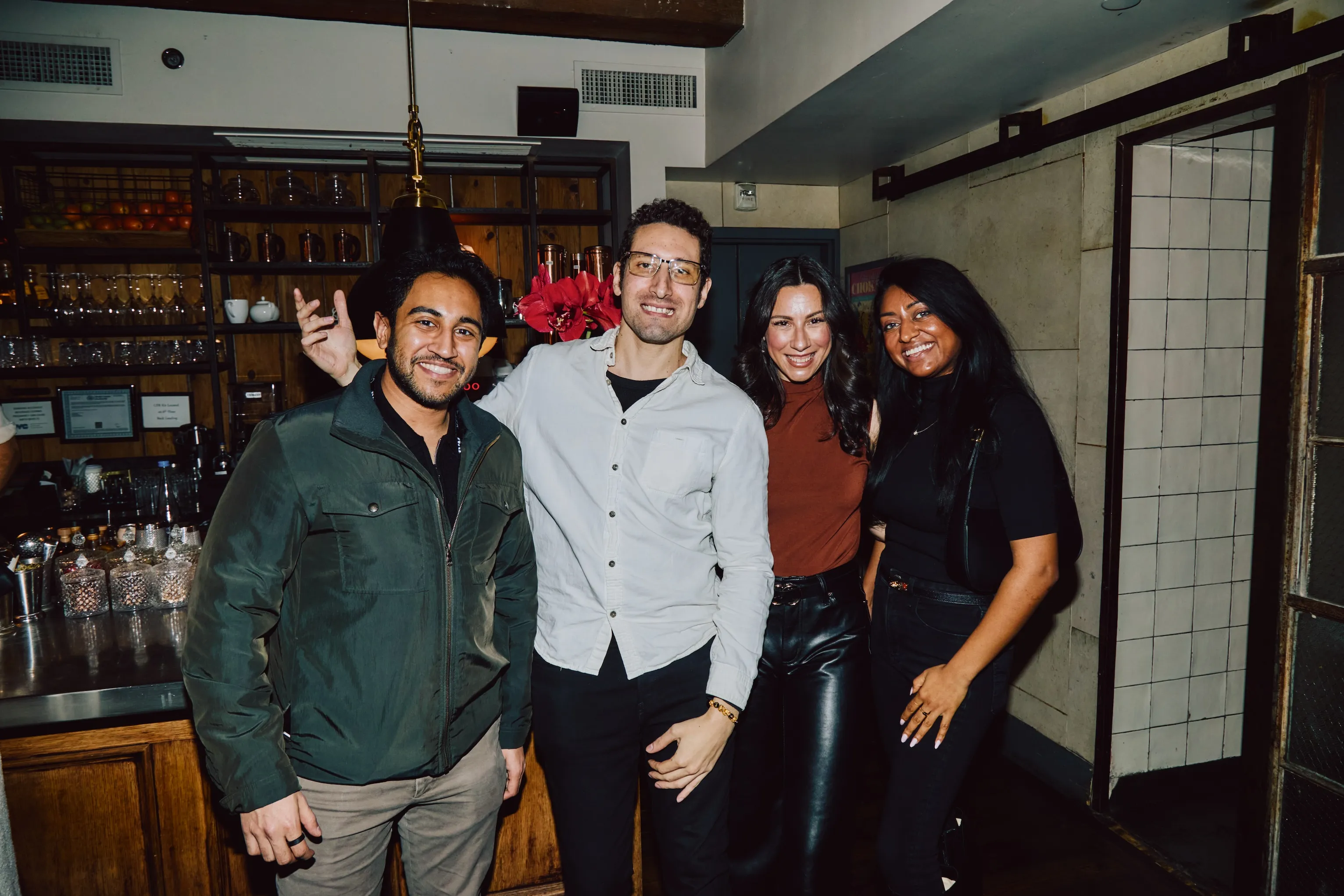 Four colleagues posing together at a bar during an ehouse team party.