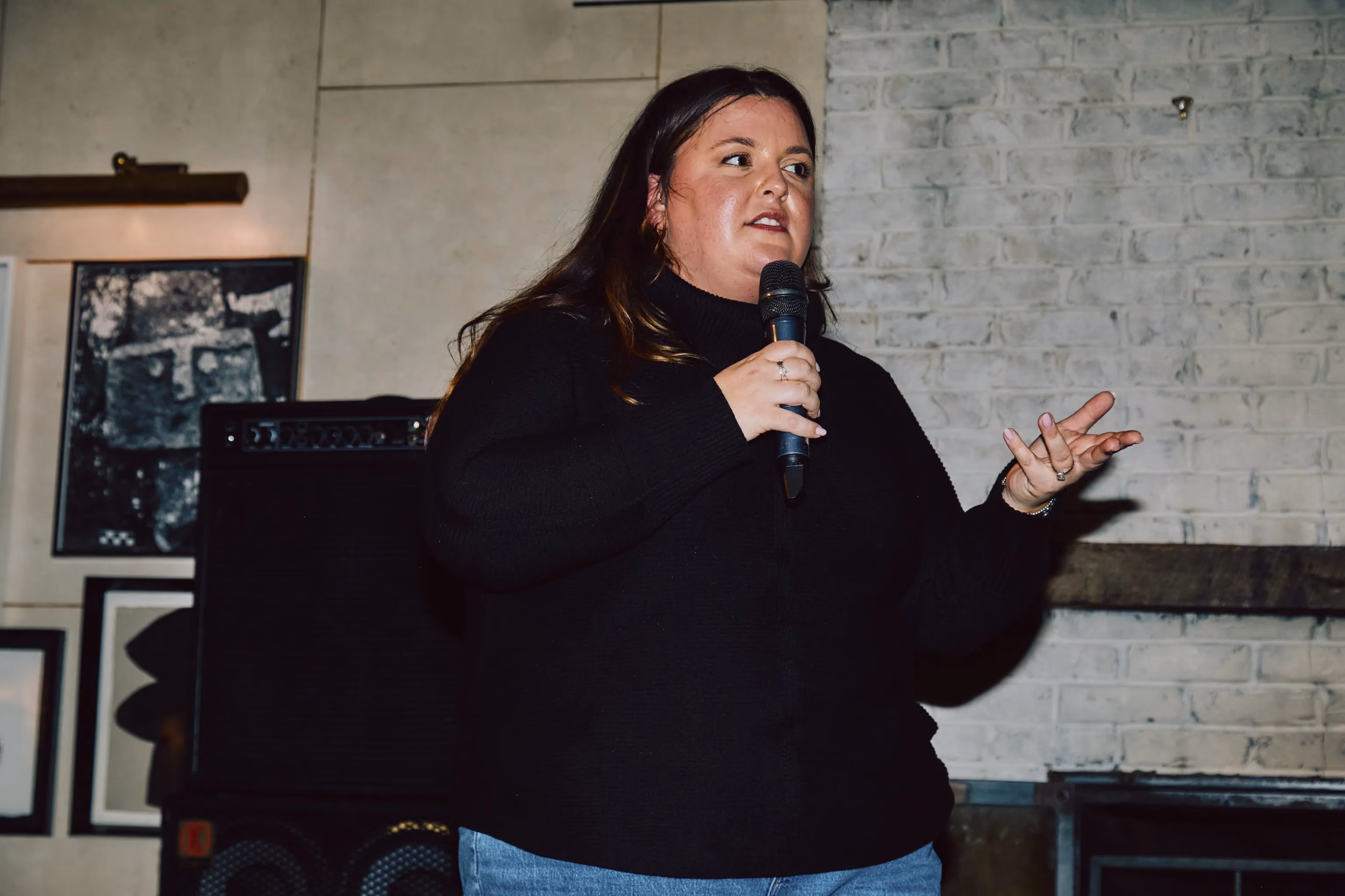 Woman speaking into a microphone while presenting at an ehouse team event.
