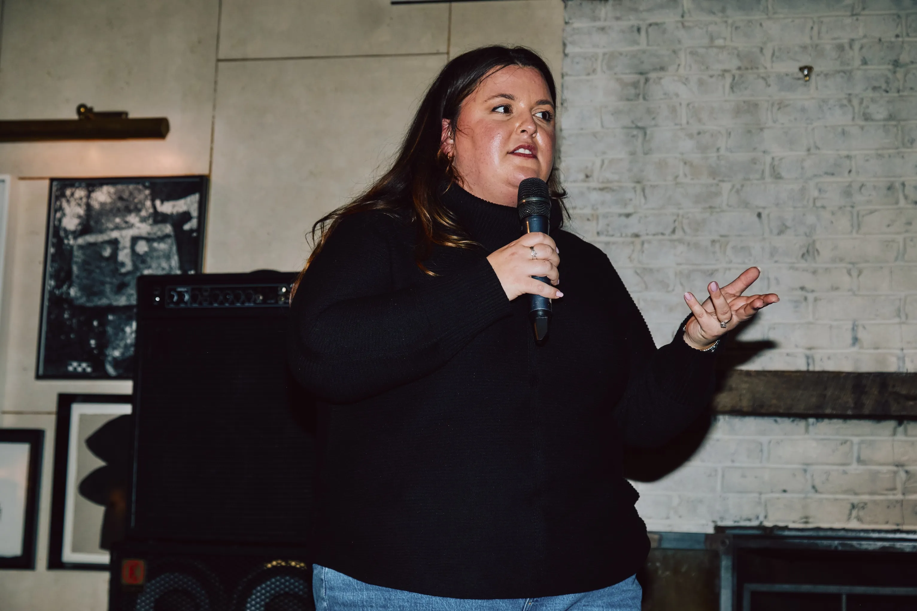 Woman speaking into a microphone while presenting at an ehouse team event.