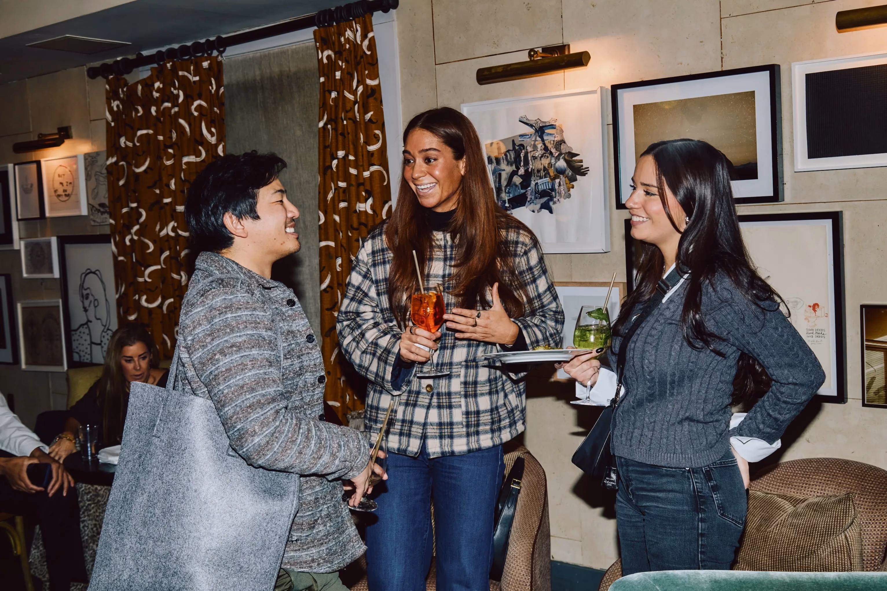 Three colleagues laughing together holding drinks at an ehouse team gathering.