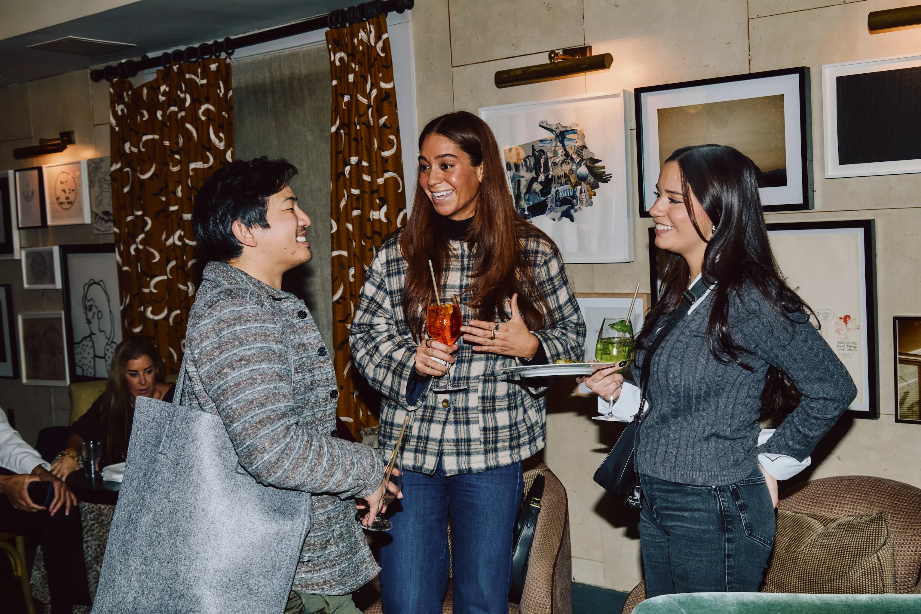 Three colleagues laughing together holding drinks at an ehouse team gathering.