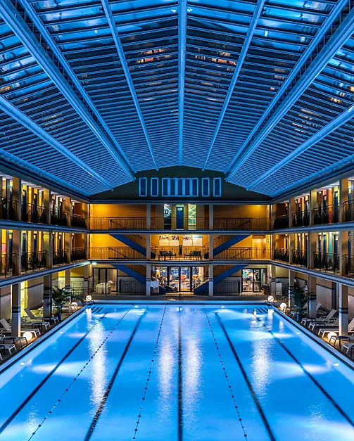 Picine incroyable de l'Hôtel Molitor Paris de nuit avec reflet bleu de l'eau dans tout l'hôtel