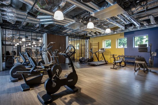 Salle de sport épurée de l'Hôtel Molitor Paris avec vélo d'entrainement et rameur pour faire des exercices de musculation