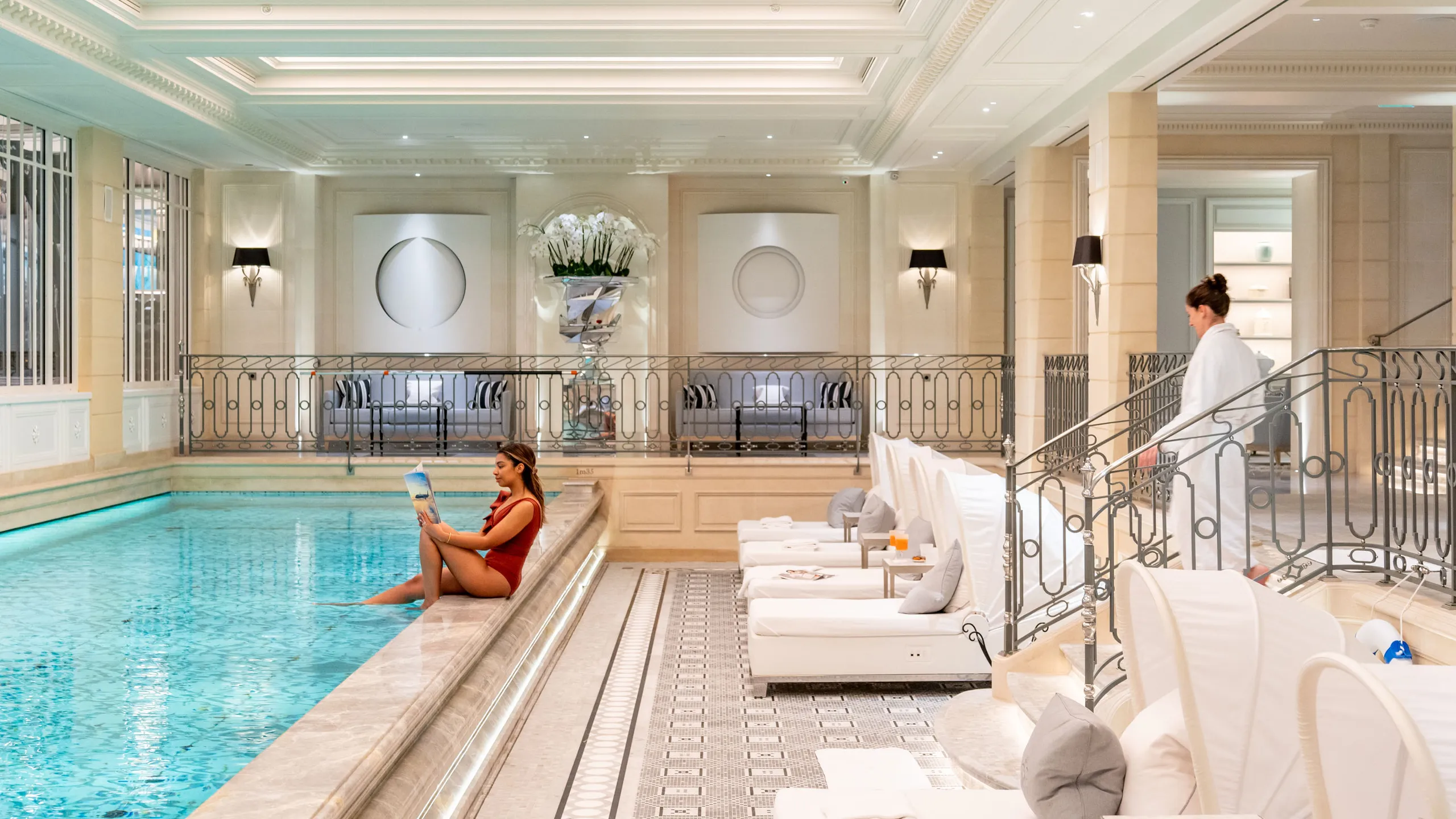 Pisicne de Four Seasons Hotel George V Paris avec femme au bord de la piscine et une autre femme entrain de sortir 'une séance de massage spa et bien être de l'hôtel