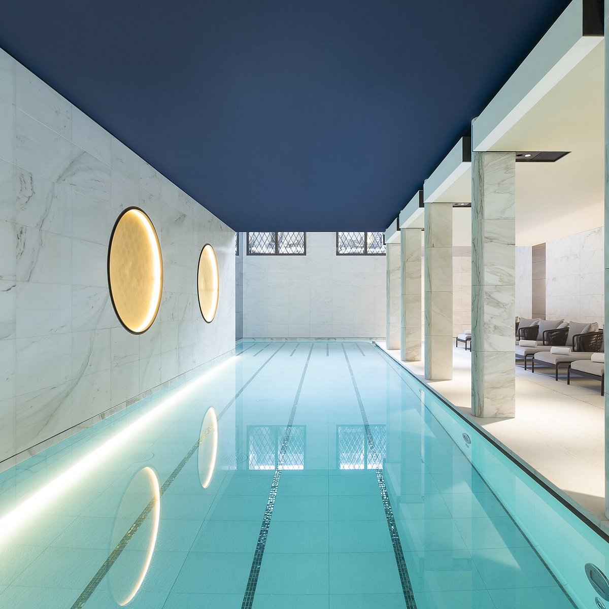 Piscine élégante de l'Hôtel Lutetia Paris avec décor bleu et transat autour et de belles colonnes de marbre