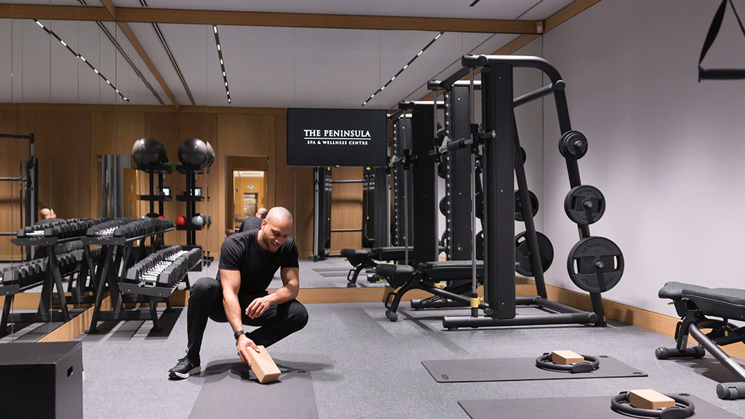 salle de itness The Peninsula Paris avec un homme entrain de faire un exercice de sport il s'agit d'un coach sportif et autour de lui des machines de musculation de la salle de sport de l'hôtel The Peninsula Paris