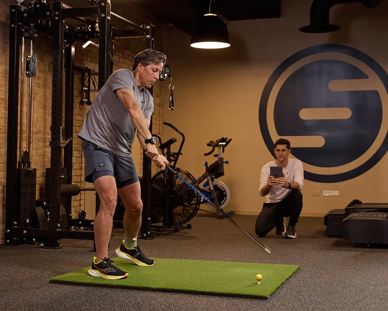 Executive working on his golf swing with the help of a concierge physical trainer at SHIFT