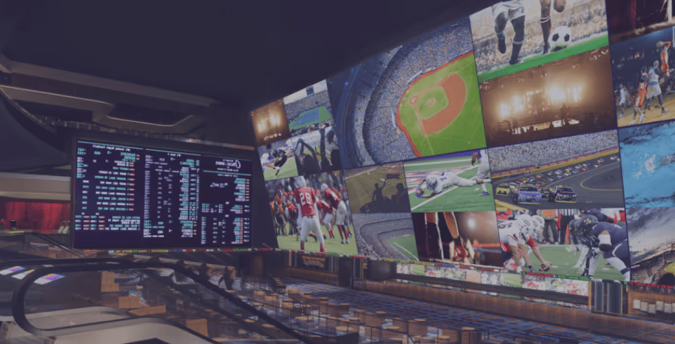 Interior of a sports betting lounge with large screens displaying multiple live sports events and betting odds.
