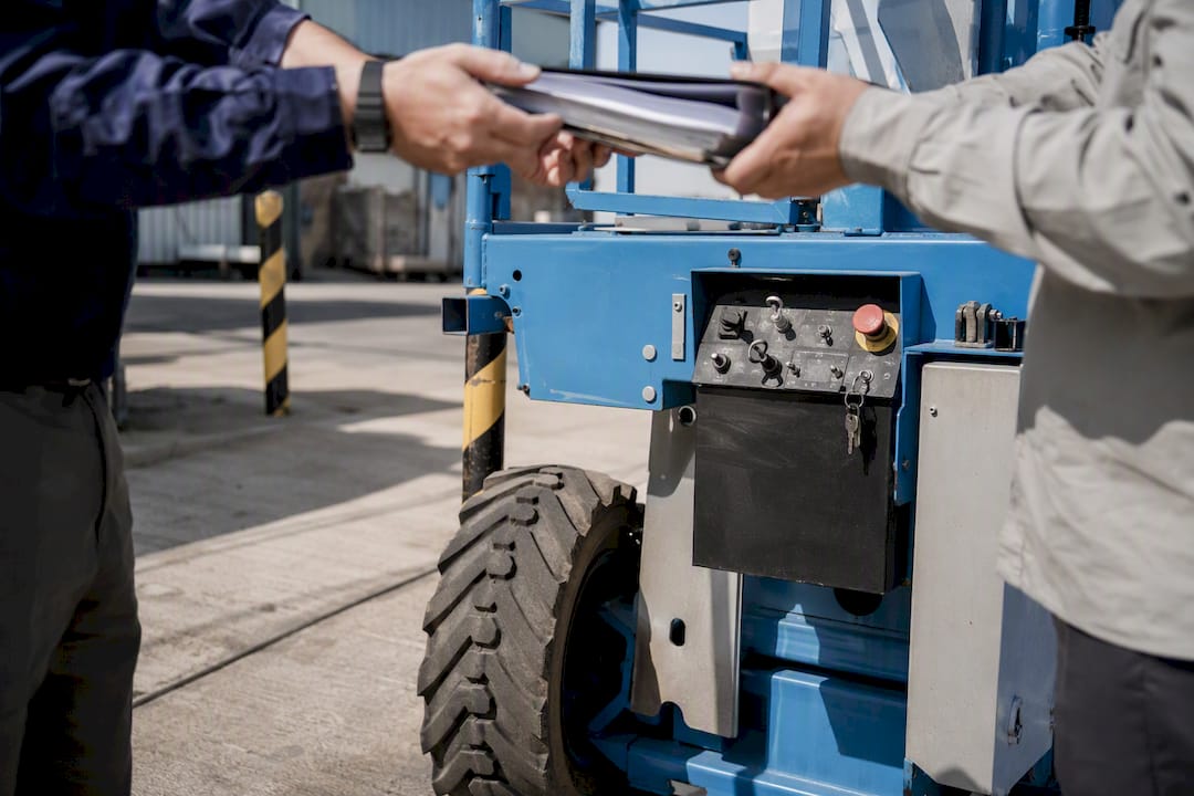 Hands exchanging keys near heavy equipment
