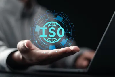 A hand holding a laptop with the word ISO on it.