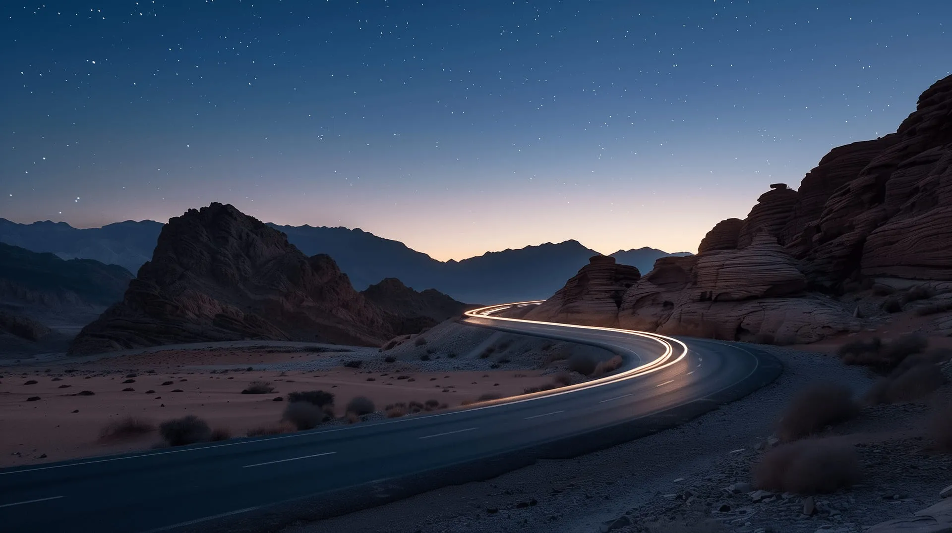 A highway at night with a mountain range in the background.