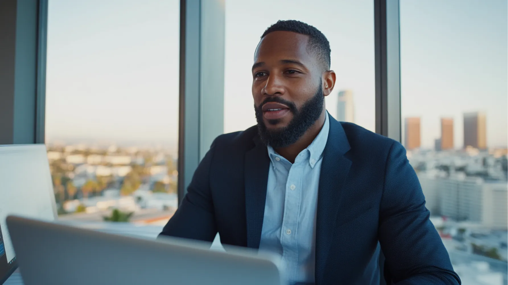 A man wearing a suit and tie sitting in front of a laptop.