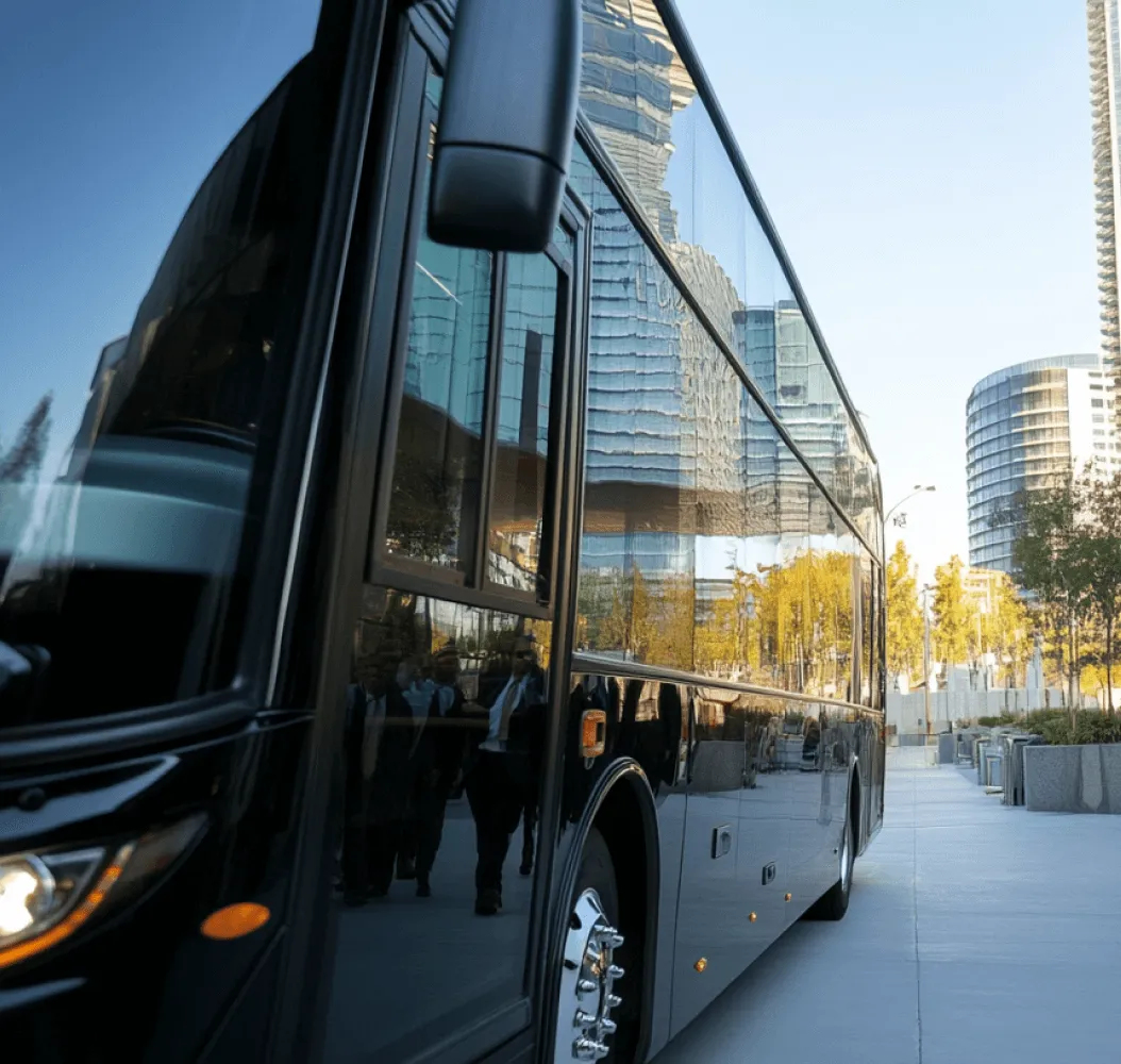 A black bus with a reflection of a city skyline in the side view mirror.