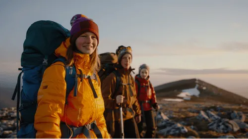 Three people with backpacks on a mountain.