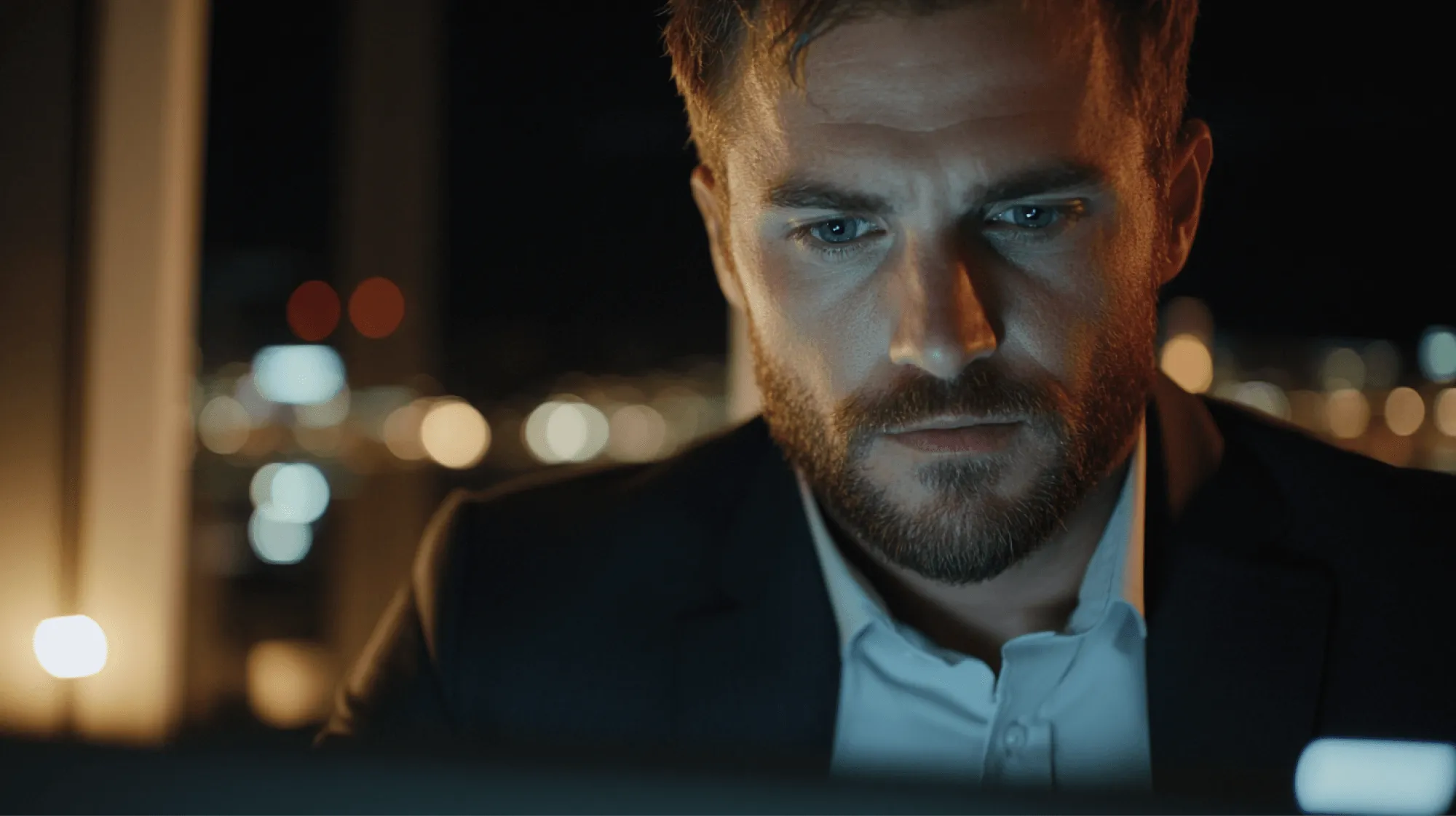 A man wearing a suit and tie looking at a computer screen.