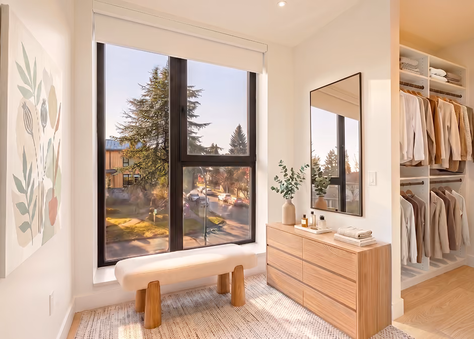 Modern bedroom with large window, neutral bedding, wood nightstands, and framed botanical prints on wall.