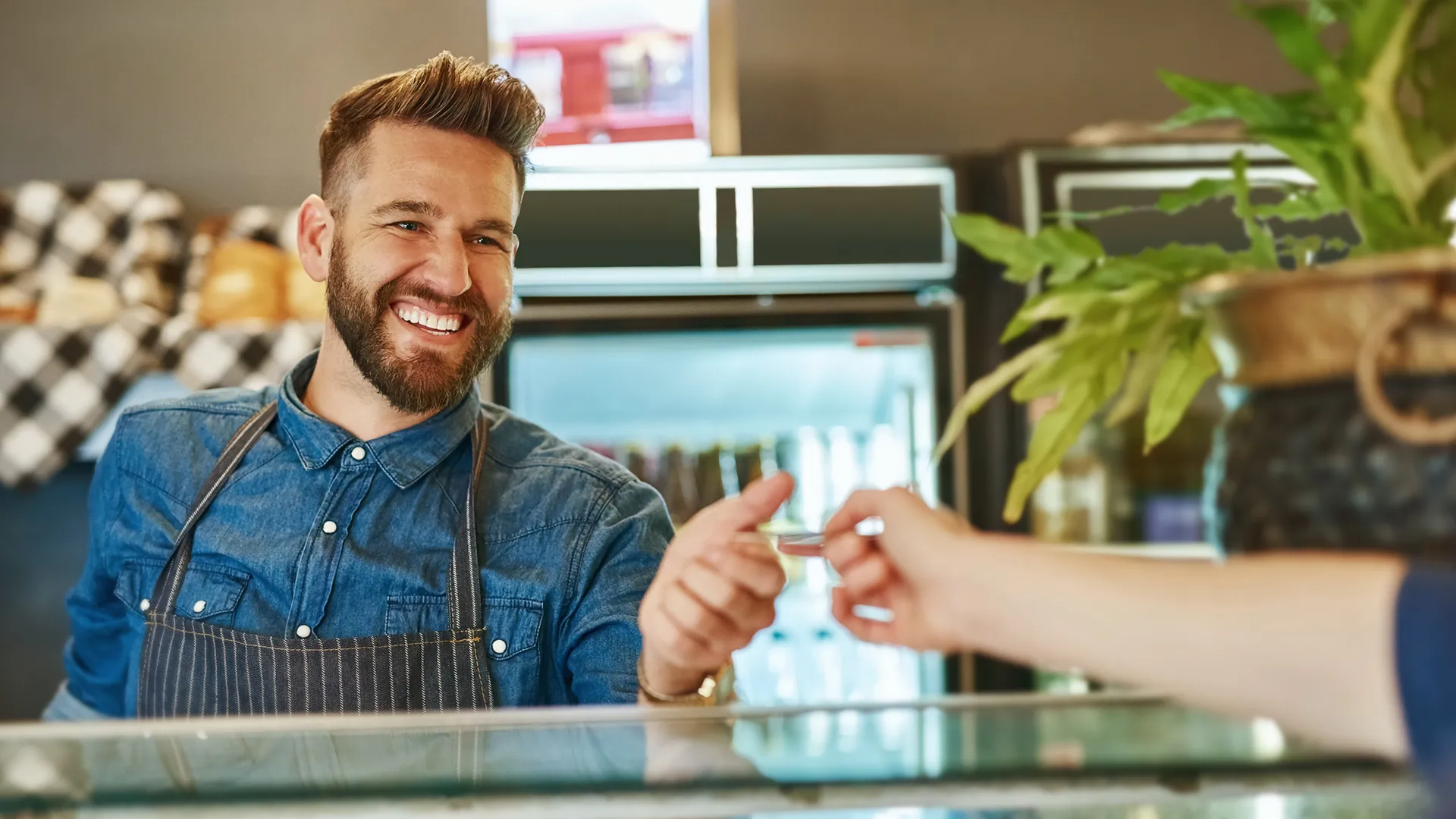 A man in an apron is handing something to a woman