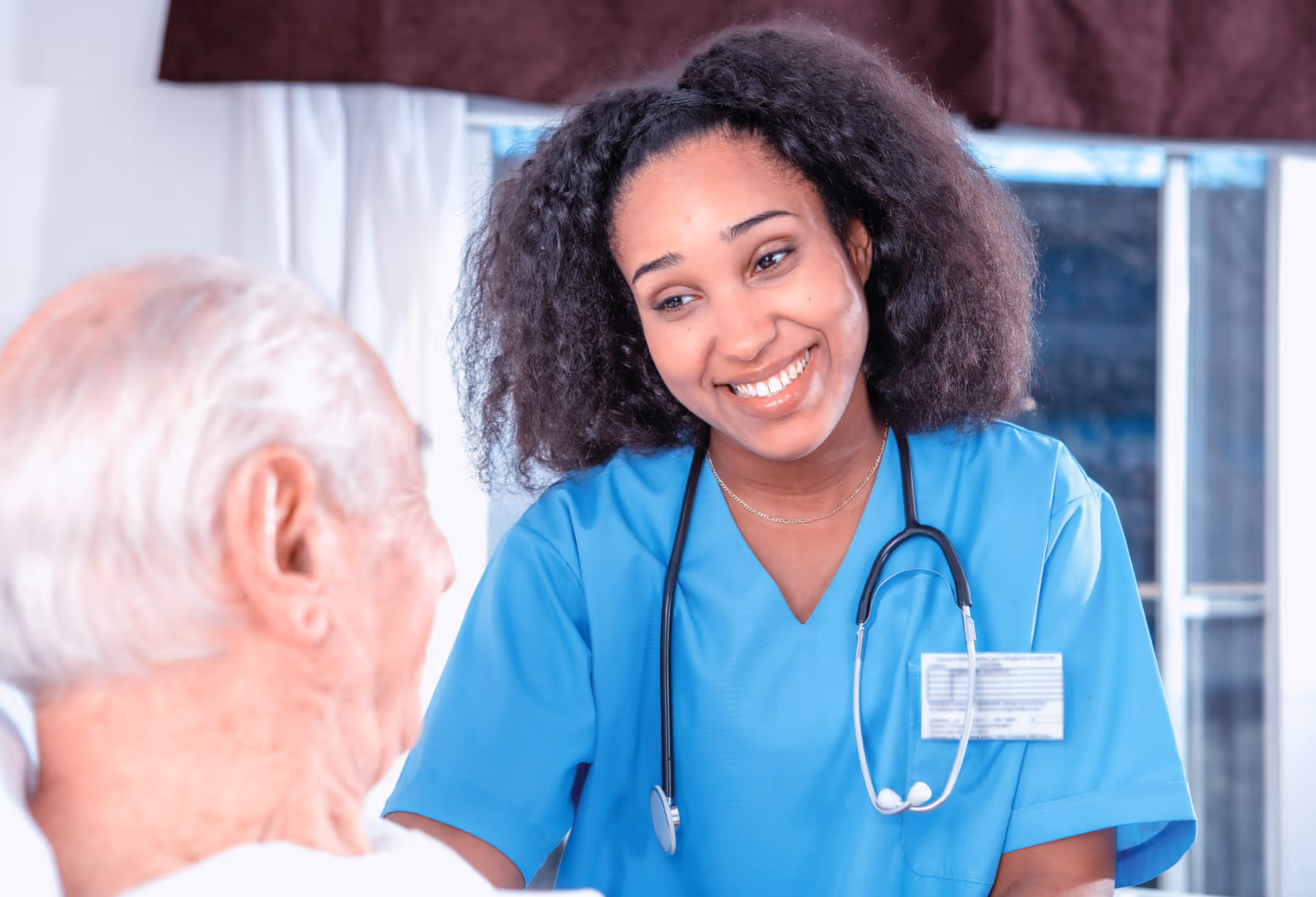 Doctor smiling at elderly patient laying in hospital bed