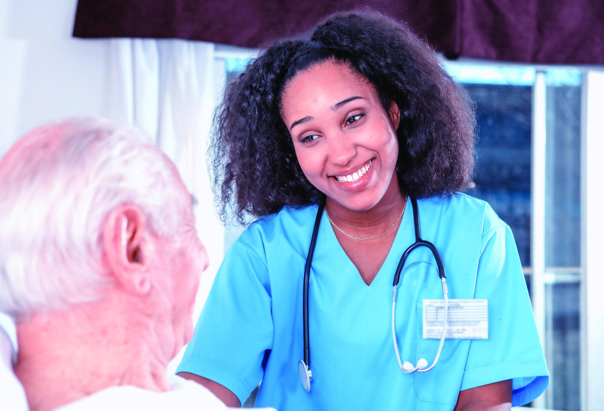 Doctor smiling at elderly patient laying in hospital bed