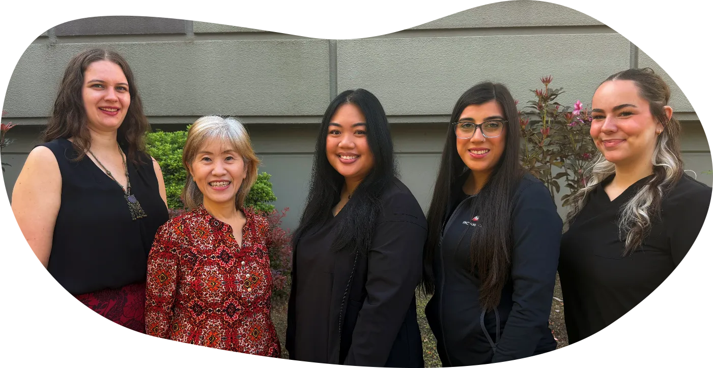 Five professional women standing outdoors in front of stairs, smiling and posing for group photo.