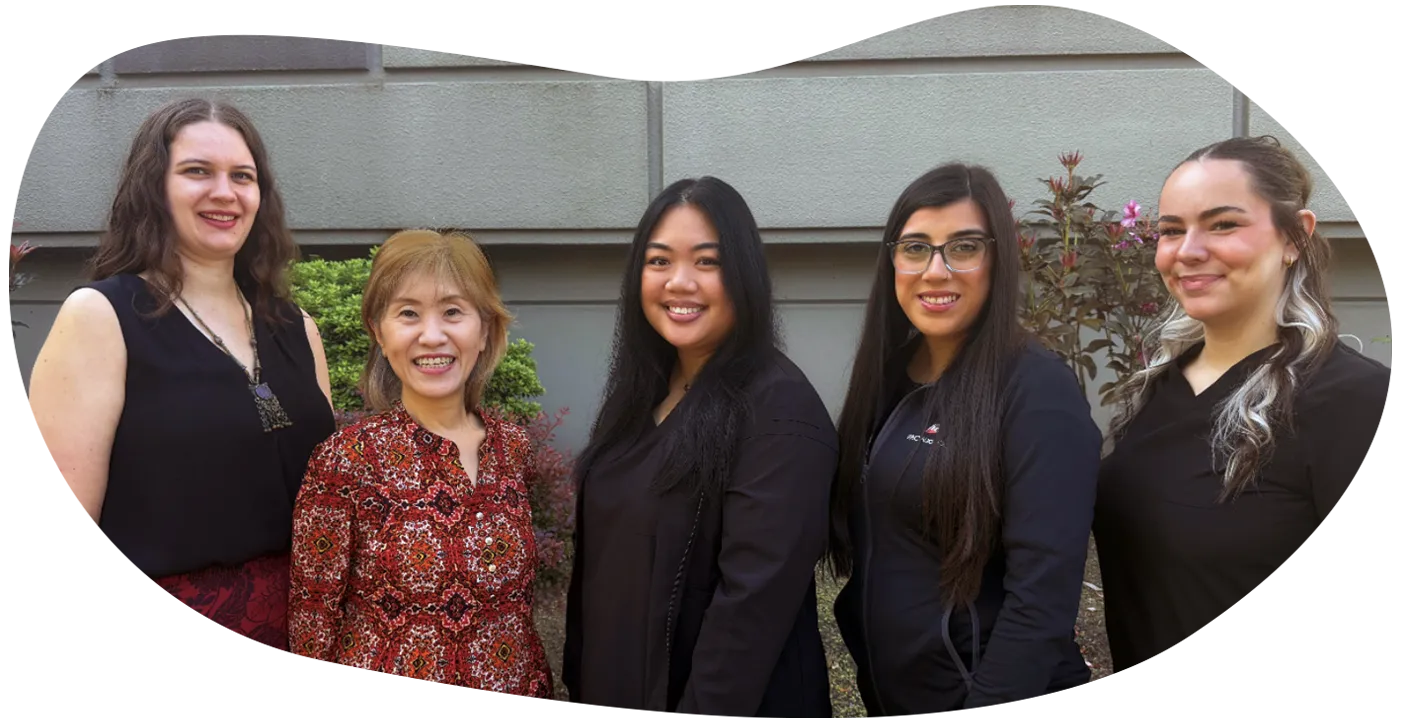 Five professional women standing outdoors in front of stairs, smiling and posing for group photo.