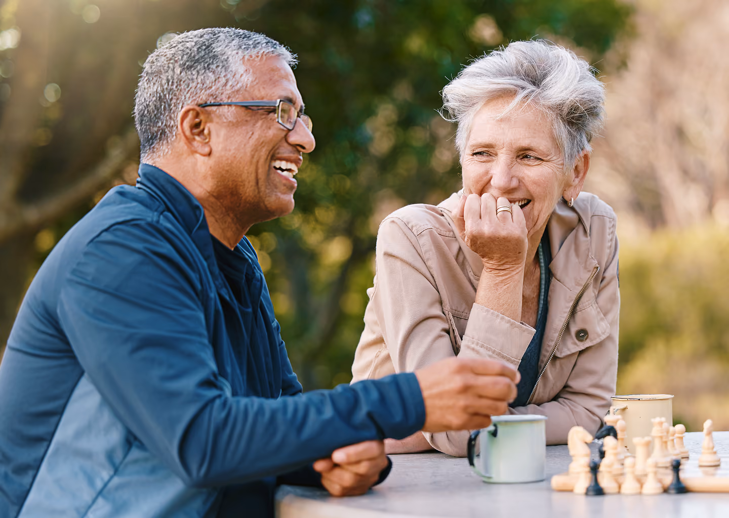 Couple laughing together over coffee and chess, representing Northeast Wealth's Creating Freedom financial strategy for people in their 50s
