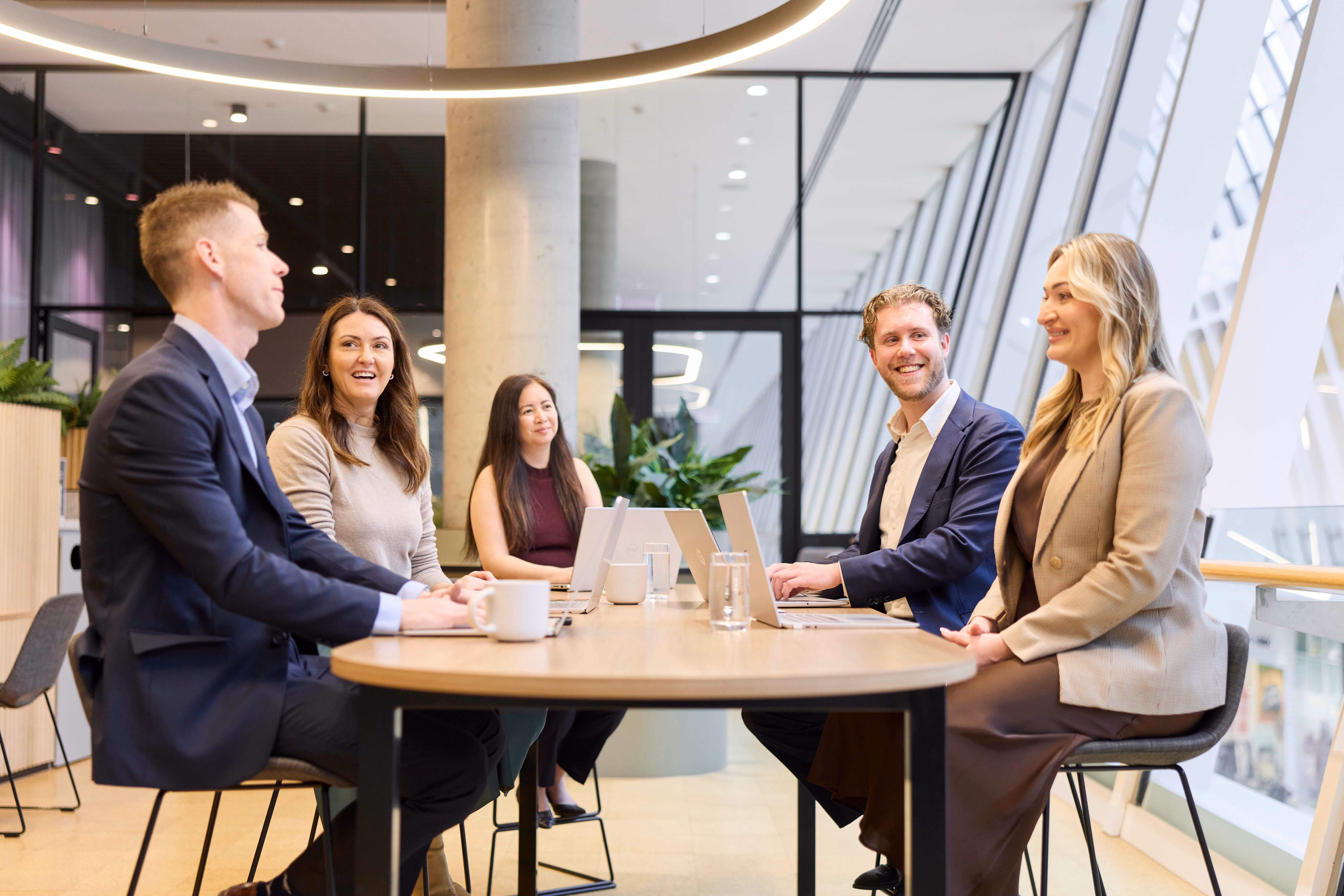 Northeast Wealth advisors collaborating around a table with laptops in their Melbourne office