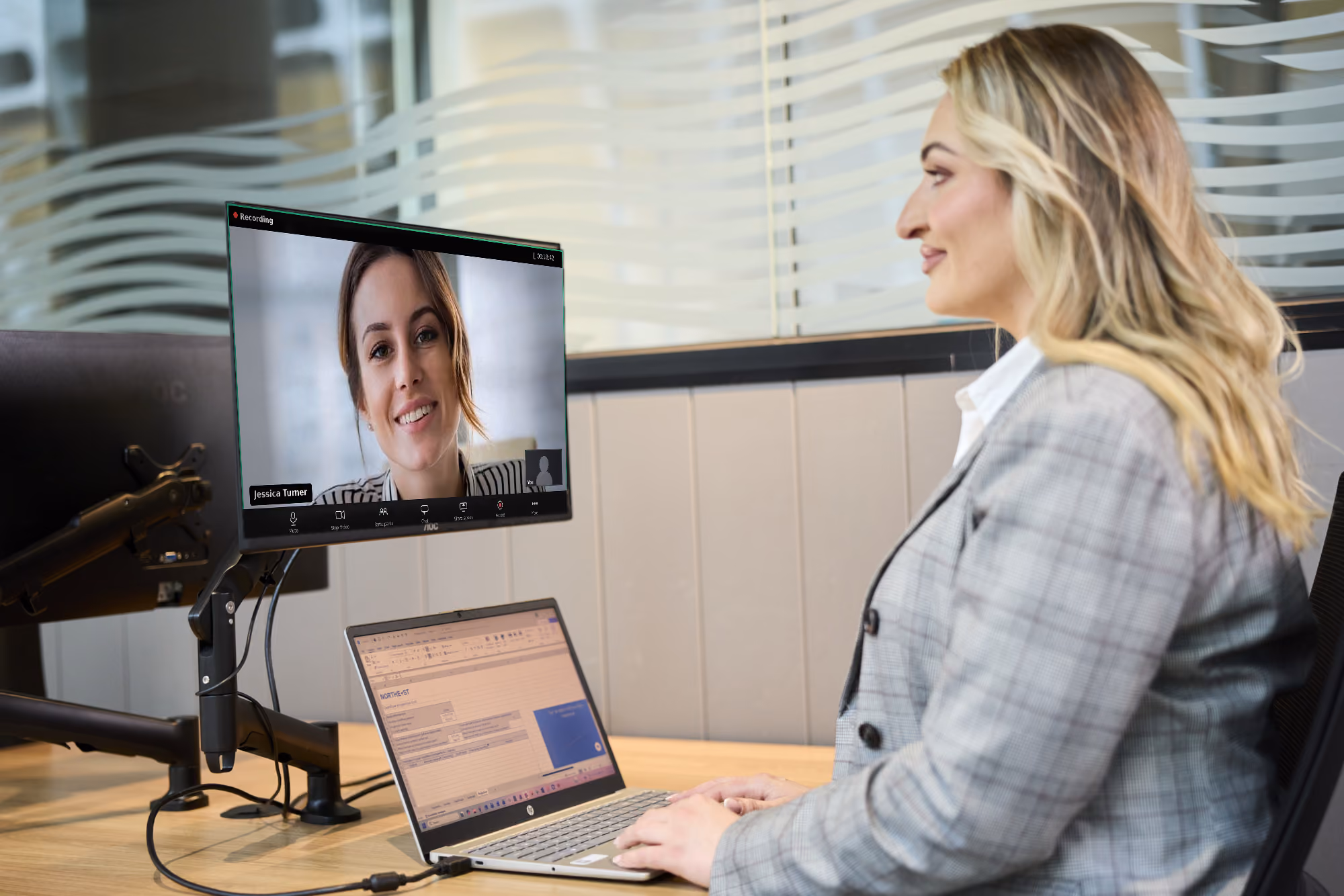 Financial advisor smiling while on a Zoom video call with a client, presentation slide on sustainable investing displayed on a second monitor, laptop showing a client onboarding form.