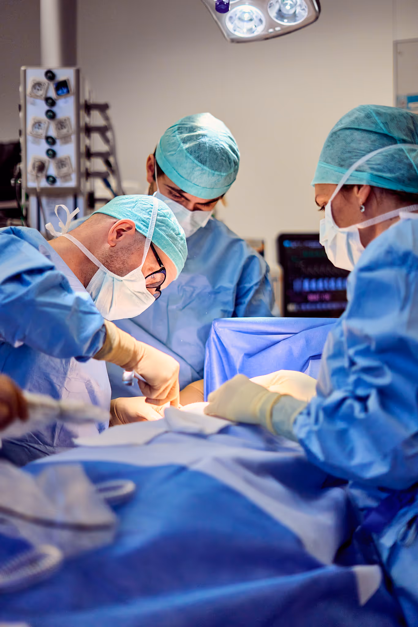 Chirurgisch team voert operatie uit onder felle lamp in operatiezaal.