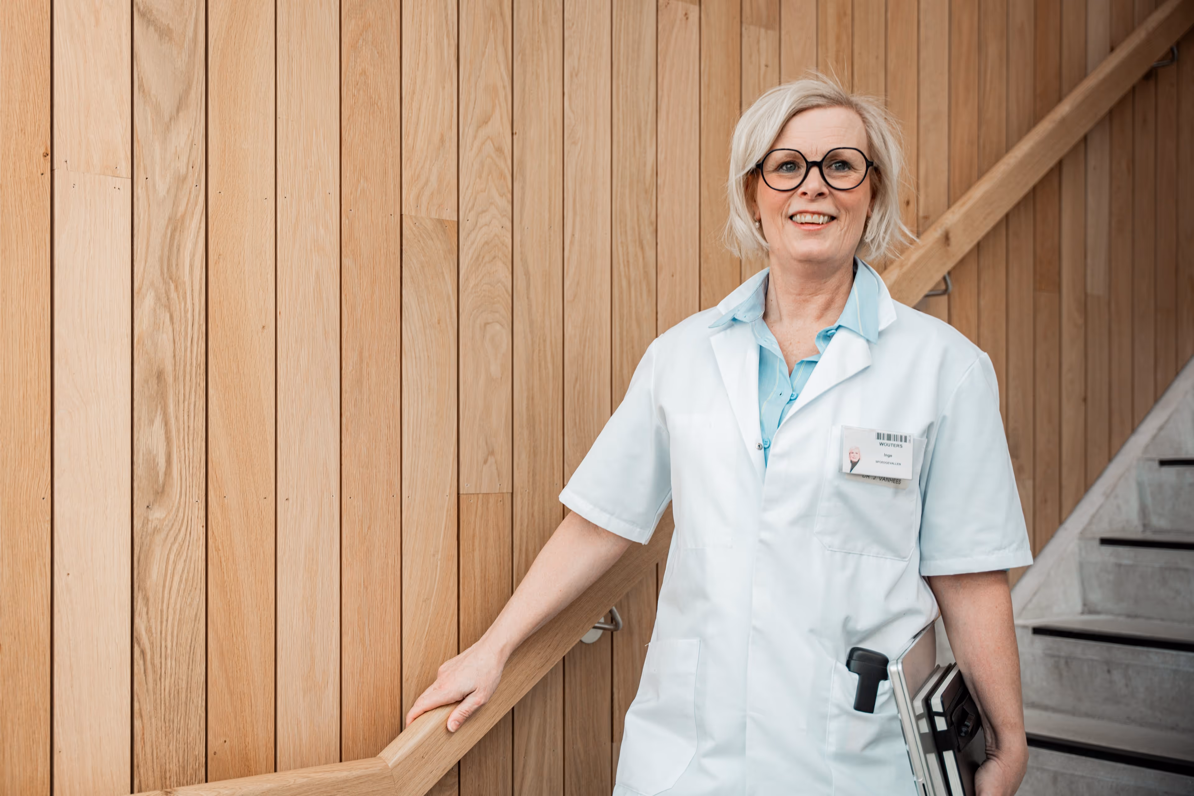 Dr. Inge Wouters in haar uniform, poserend op de trap met een houten muur als achtergrond.
