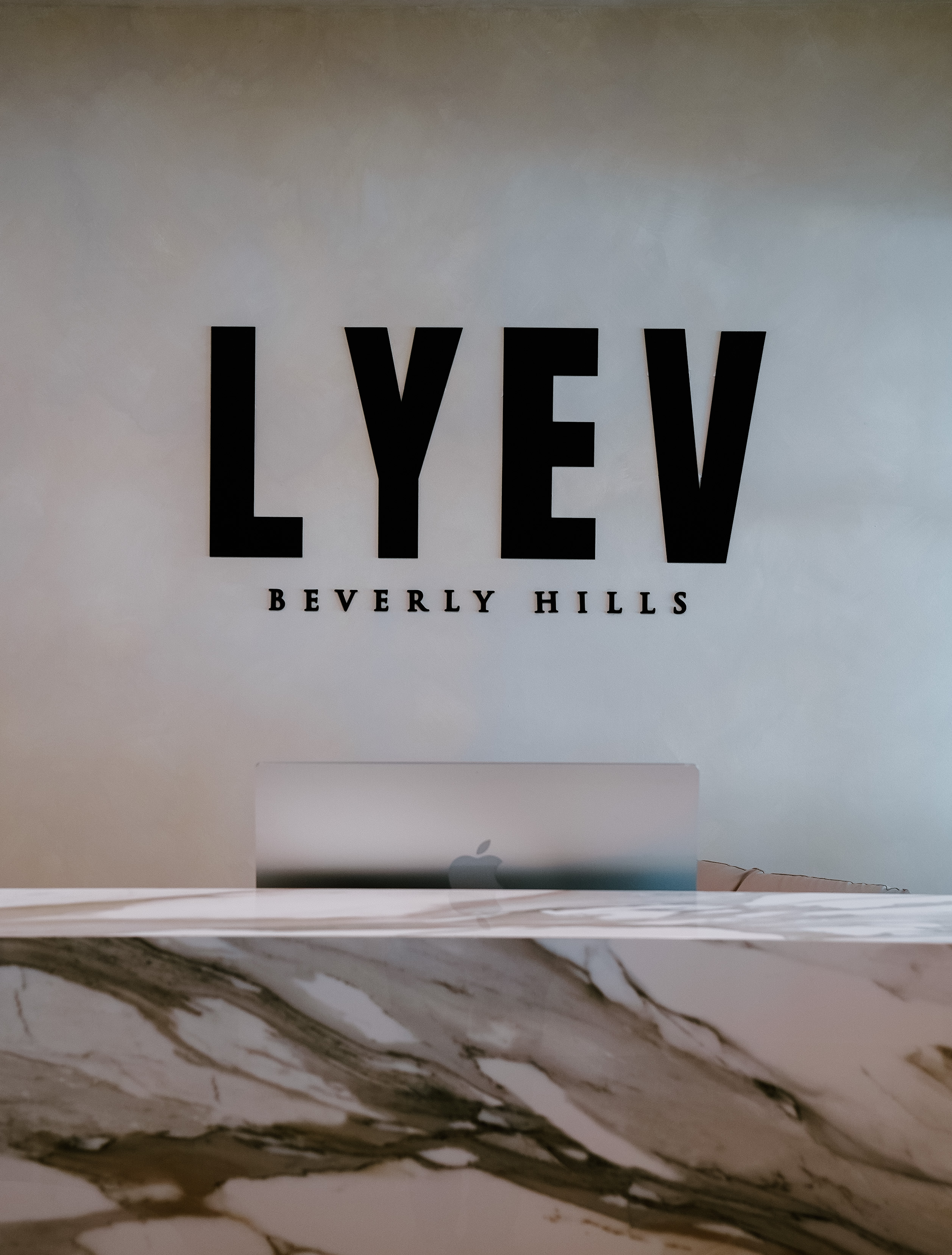 LYEV Beverly Hills wall sign above the clinic’s marble reception desk.