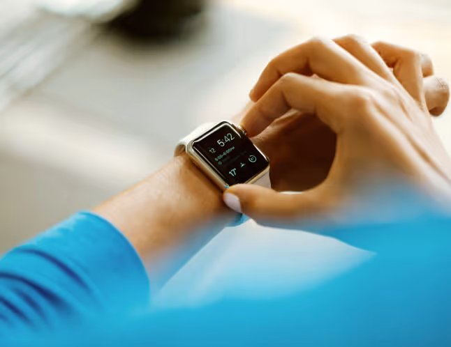 Person adjusting a smartwatch on their wrist displaying the time 5:42 and weather information.