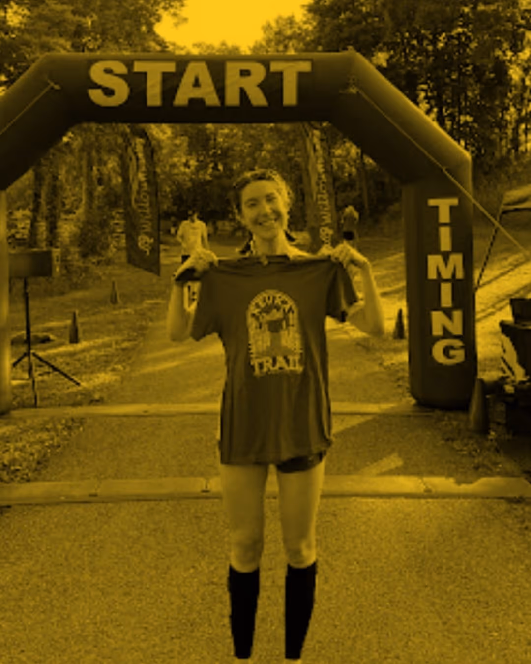 Wild Dog Athletics endurance runner client finishes her race posing with her medal.