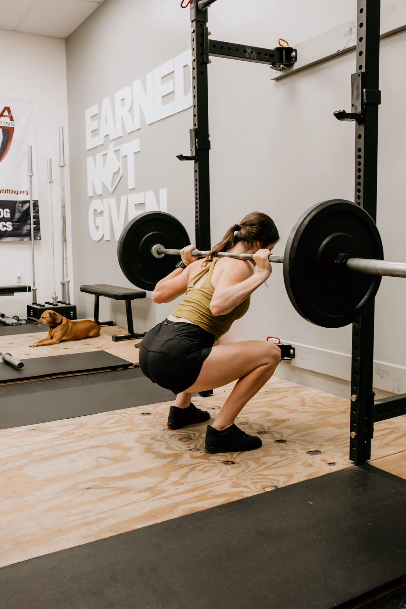 Strength and conditioning coach Abby of Wild Dog Athletics squatting with a barbell.