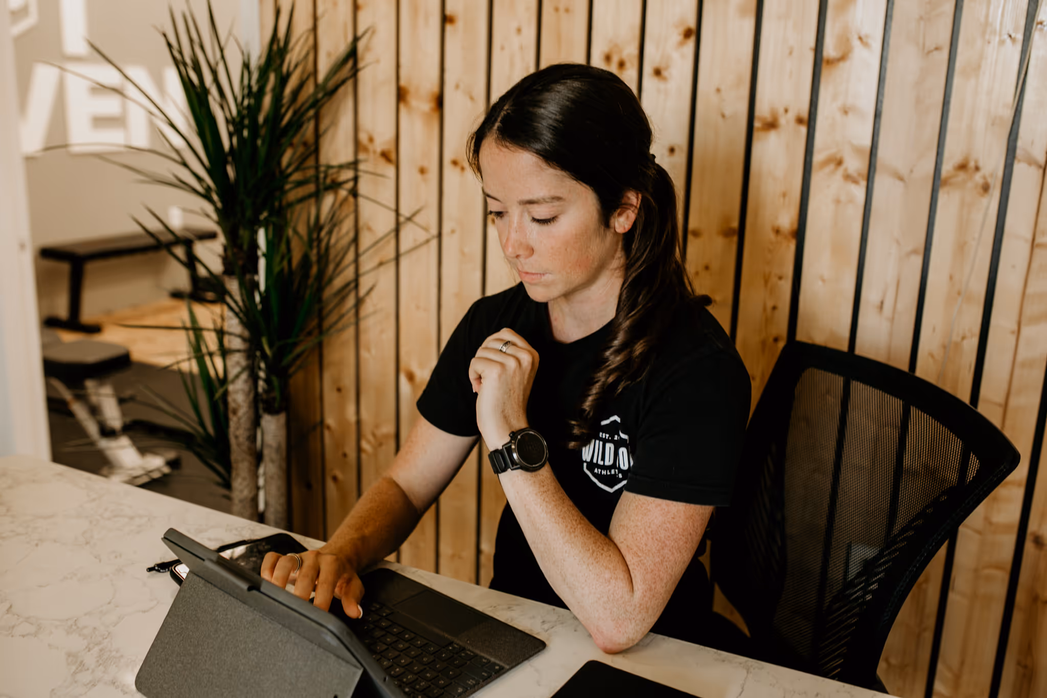 Coach Abby of Wild Dog Athletics on her laptop working with her remote client.
