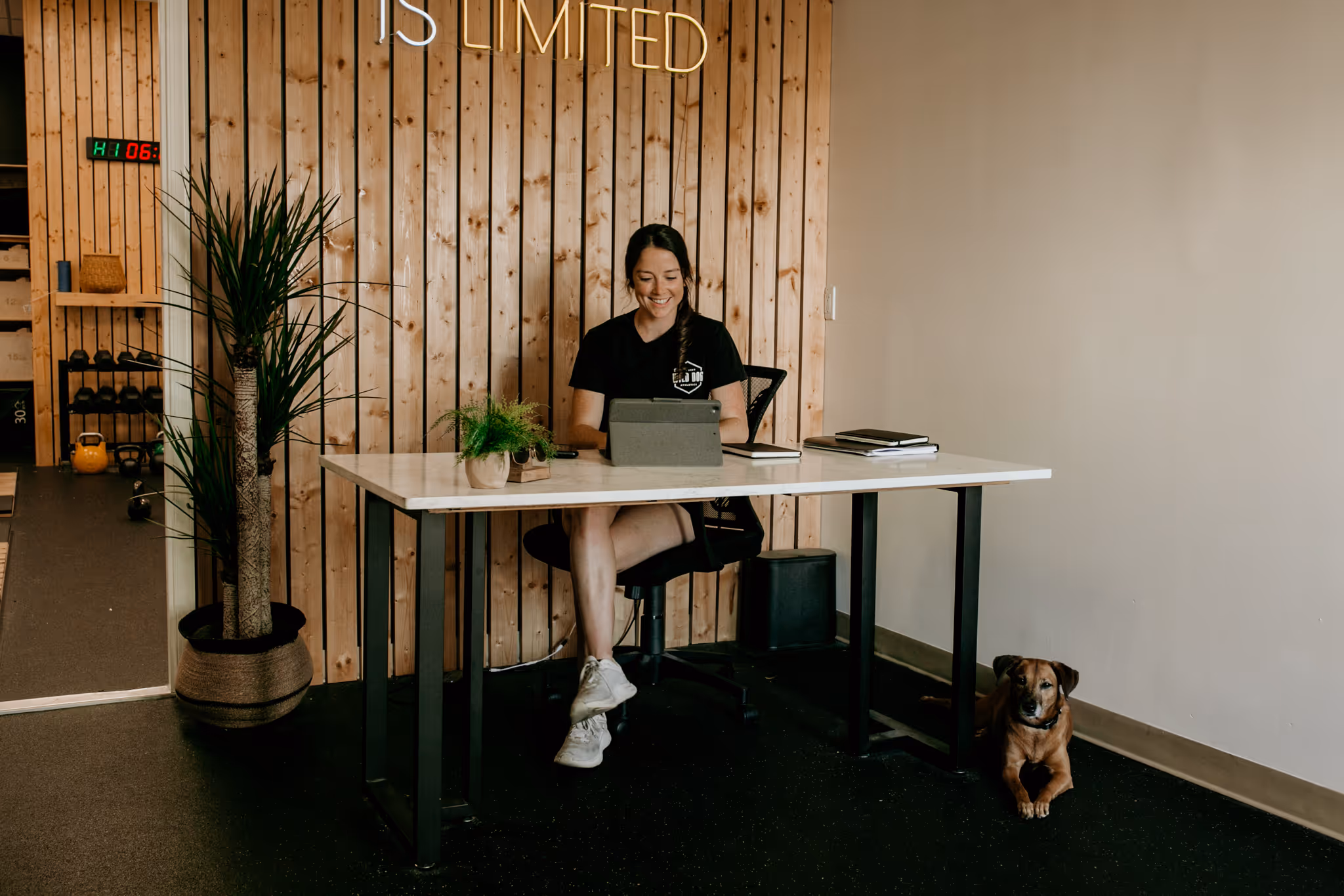 Coach Abby of Wild Dog Athletics poses in her athletic training gym office where she works with remote clients.