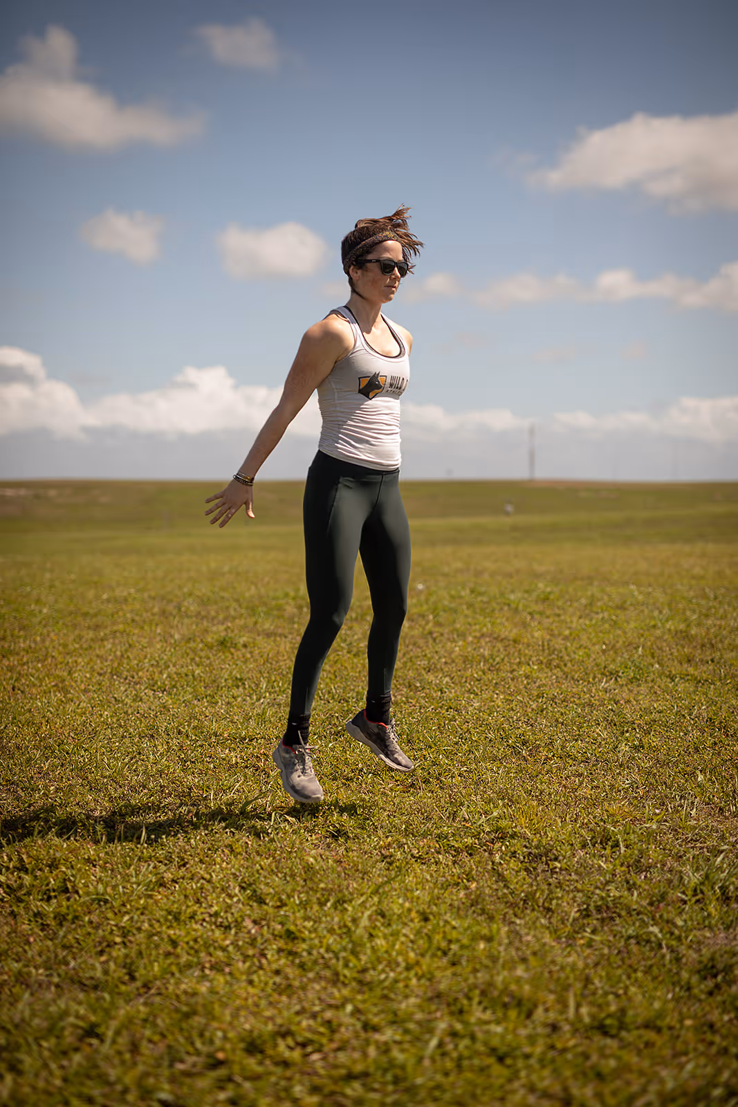 Remote running coach Abby of Wild Dog Athletics performs exercises in a field before trail running.